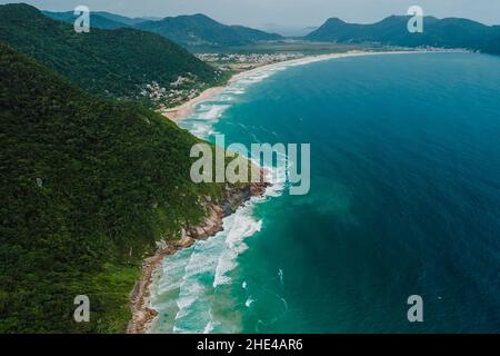 Costa tropicale con montagne e oceano Atlantico con onde in Brasile. Vista aerea Foto Stock