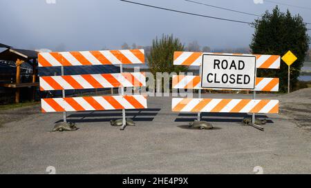 Garofano, WA, USA - 31 ottobre 2021; Un cartello stradale chiuso e un paio di barriere a strisce bloccano una strada rurale Foto Stock