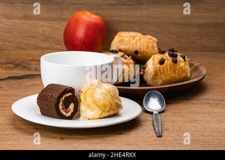 Deliziosa pausa caffè con vari dessert in ceramica bianca con una tazza di caffè e mela rossa matura. Delizioso dessert fatto in casa, Mini Black Fore Foto Stock