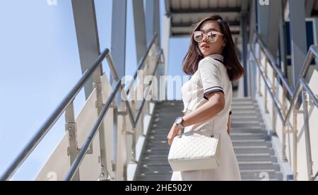 street fashion su asian business woman su scala pubblica passo per la stazione dello skytrain Foto Stock