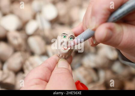 07 gennaio 2022, Sassonia-Anhalt, Thale: I bianchi di testa per le statuette delle streghe sono dipinti a mano. La strega di Brocken e le figurine del diavolo sono fatte a mano nel Thalenser Hexenmanufaktur e sono famosi souvenir di resina. In varie dimensioni e anche su misura, le figure sono costituite da un massimo di 20 parti, che vengono prodotte in officina della manifattura. Gli ordini per le figurine provengono anche dall'estero. I dipendenti della fabbrica di streghe utilizzano i mesi invernali principalmente per progettare nuove figurine di streghe e per pre-produrle. Foto: Matthias Bein/dpa-Zentralbild/ZB - ATTENZIONE: Solo per uso editoriale in Foto Stock