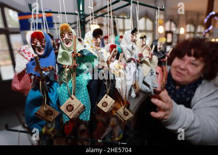 07 gennaio 2022, Sassonia-Anhalt, Thale: Martina Siebert-Sperrling dalla manifattura delle streghe mostra numerose figurine delle streghe appese su uno stand di vendita. Nel Thalenser Hexenmanufaktur, la strega di Brocken e le figurine del diavolo sono fatte a mano e sono famosi souvenir di resina. In varie dimensioni e anche su misura, le figure sono costituite da un massimo di 20 parti, che vengono prodotte in officina della manifattura. Gli ordini per le figurine provengono anche dall'estero. I dipendenti della fabbrica di streghe utilizzano i mesi invernali principalmente per progettare nuove figurine di streghe e per pre-produrle. Foto: Matthias Bein/dpa Foto Stock