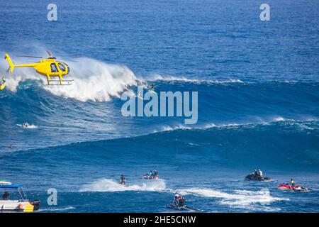 Un elicottero che filma un surfista trainato a Peahi (JAWS) al largo di Maui. Hawaii. Questa è stata una giornata media al famoso surf spot. Foto Stock