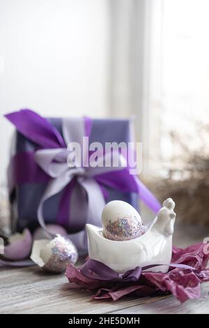 Composizione pasquale con un uovo e un regalo su sfondo sfocato. Foto Stock