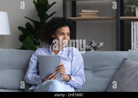 Giovane donna africana sognante con tablet digitale. Foto Stock
