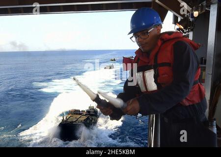 Il marinaio segnala a un veicolo d'assalto anfibio che entra nell'acqua dal cancello di poppa della USS Ashland. (37182870081). Foto Stock