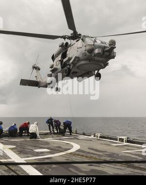 I marinai sul ponte di volo di USS Antietam (CG-54) inviano campioni di carburante durante il rifornimento di carburante di HSM-60R MH-780 in volo. Foto Stock