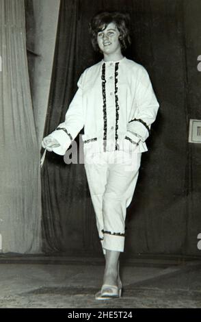 Modella femminile passeggiando sulla rampa di piattaforma in una sfilata indoor di moda nel 1960s, Bulgaria, Europa orientale Foto Stock