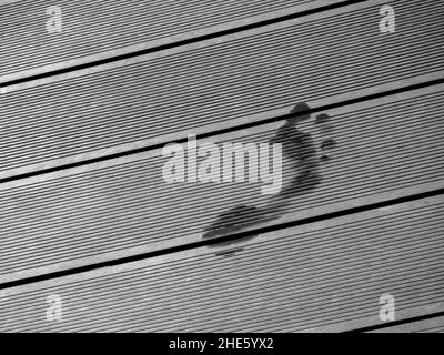 Le impronte bagnate sul lato destro sul pavimento di una piscina con spazio copia, concetto estivo. Foto Stock