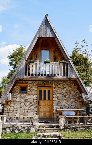 Casa triangolare a due piani con terrazza, tavolo e panca all'ingresso. Montenegro Foto Stock