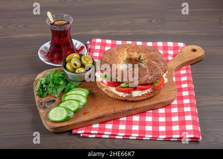 Panino turco Bagel Simit. Bagel vegano fatto a casa con formaggio, pomodoro e cetriolo su sfondo ligneo. Colazione turca veloce Foto Stock