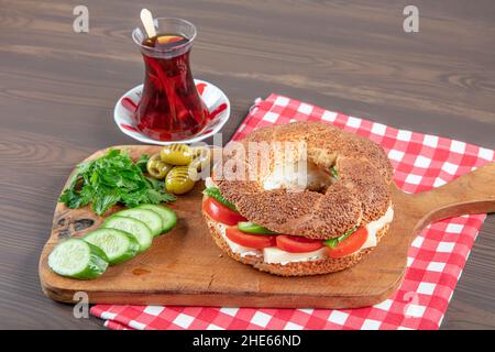 Panino turco Bagel Simit. Bagel vegano fatto a casa con formaggio, pomodoro e cetriolo su sfondo ligneo. Colazione turca veloce Foto Stock