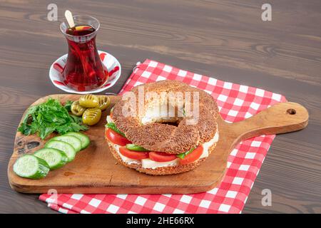 Panino turco Bagel Simit. Bagel vegano fatto a casa con formaggio, pomodoro e cetriolo su sfondo ligneo. Colazione turca veloce Foto Stock