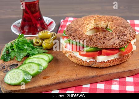 Panino turco Bagel Simit. Bagel vegano fatto a casa con formaggio, pomodoro e cetriolo su sfondo ligneo. Colazione turca veloce Foto Stock
