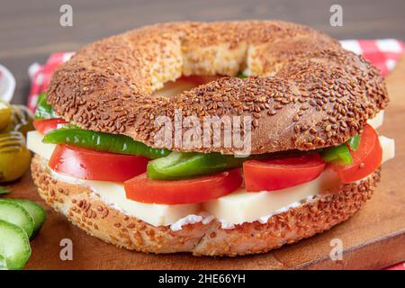 Panino turco Bagel Simit. Bagel vegano fatto a casa con formaggio, pomodoro e cetriolo su sfondo ligneo. Colazione turca veloce Foto Stock