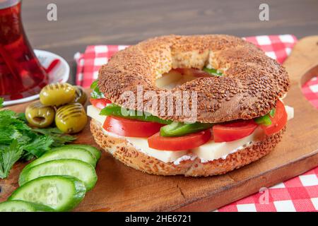Panino turco Bagel Simit. Bagel vegano fatto a casa con formaggio, pomodoro e cetriolo su sfondo ligneo. Colazione turca veloce Foto Stock
