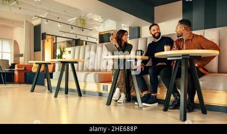 Tre uomini d'affari che lavorano in una lobby d'ufficio. Team di uomini d'affari felici sorridendo mentre si ha una discussione. Gruppo di imprenditori moderni coll Foto Stock