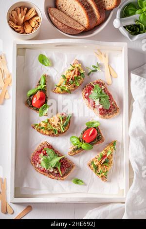 Bruschetta sana con pesto e pomodoro per colazione su un bordo di servizio. Foto Stock
