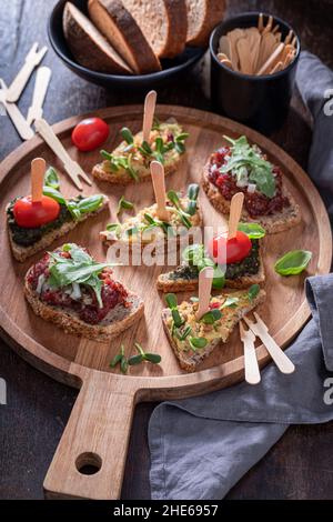 Bruschetta fatta in casa con pesto e pomodoro per colazione su un bordo di servizio. Foto Stock