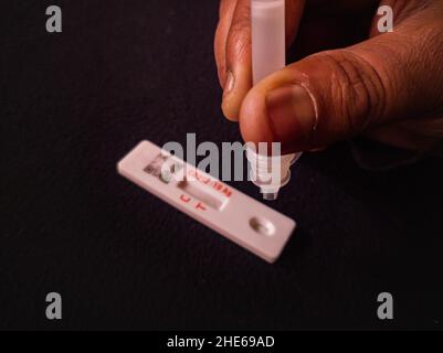 covid19 o nuovo test per coronavirus omicron con metodo rapid antigen. gocce di soluzione di antigene estratto gocciolando a mano sul kit di auto-test. shot prelevato al buio Foto Stock