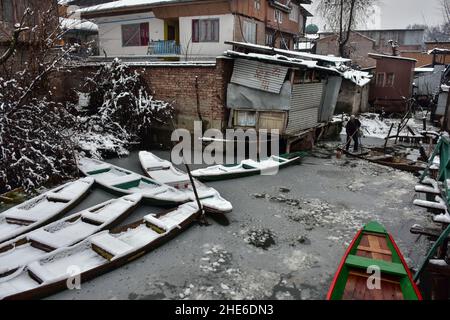 Srinagar, India. 08th Jan 2022. Un boatman fa la sua barca negli interni del lago dal durante la nevicata a Srinagar.Kashmir continua a rimanere tagliato fuori dal resto del paese il sabato dopo la nevicata continua. Il tempo ha previsto 'graduale diminuzione' dell'intensità delle precipitazioni per sera e significativo miglioramento del tempo entro Domenica mattina credito: SOPA Images Limited/Alamy Live News Foto Stock