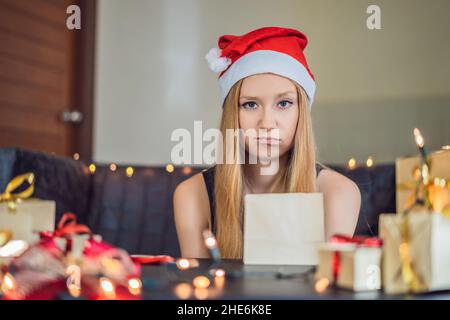 Giovane donna si presenta di imballaggio. Presente avvolto in carta artigianale con un rosso e oro nastro per Natale o Capodanno. La donna fa un calendario d'Avvento Foto Stock