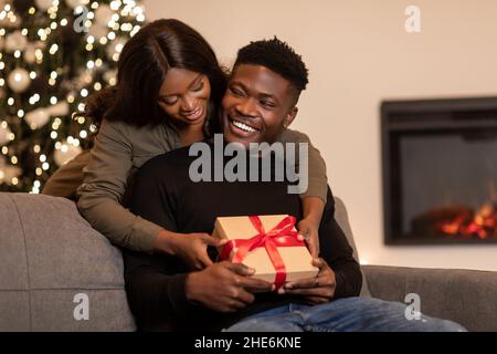 La moglie nera regala un regalo al marito per festeggiare il San Valentino al coperto Foto Stock