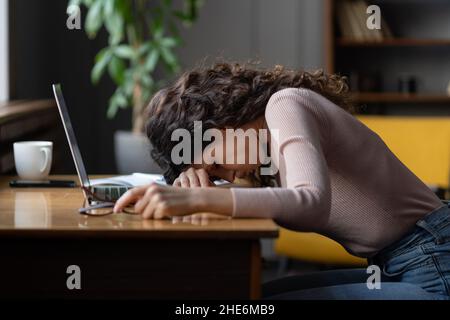 Burnout di lavoro. Dipendente femminile stanco che mette testa giù sul tavolo, che soffre di stress cronico del lavoro. Foto Stock