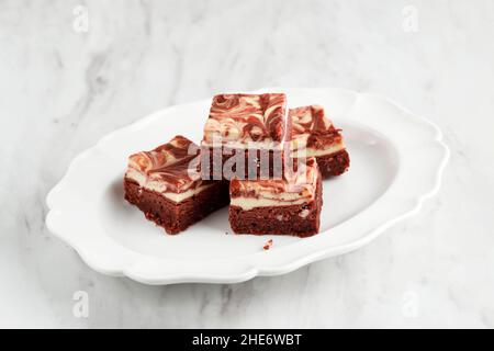 Crema di velluto rosso brownie di formaggio su piastra in ceramica bianca, isolato Foto Stock