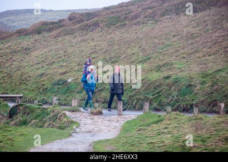 Godrevy, Cornovaglia, 9th gennaio 2022, gente fuori per una passeggiata mattutina in una giornata grigia, umida e triste a Godrevy, Cornovaglia. Sorprendentemente, alcune persone passeggiavano lungo le scogliere per guardare le foche e il faro di Godrevy anche se la temperatura era di 9C, ma con il fattore windchill sembrava molto più freddo.Credit: Keith Larby/Alamy Live News Foto Stock