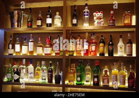 Bottiglie di whisky vodka cognac su ripiani in legno al bar del ristorante Foto Stock