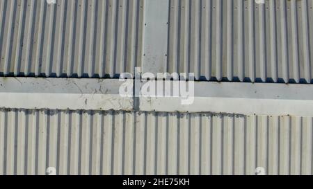 Ispezione aerea del tetto di una fabbrica di tetti in metallo, mostrando il crinale con alcune riparazioni Foto Stock