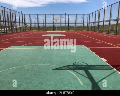 Un campo di pallacanestro vuoto all'aperto in una giornata di sole Foto Stock