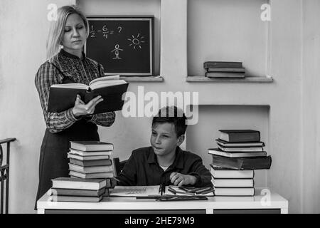 Una tutor femminile insegna a casa un ragazzo. Foto in bianco e nero. Foto Stock