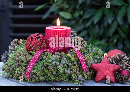 decorazione di natale con candela rossa e corona di bacche di ginepro Foto Stock