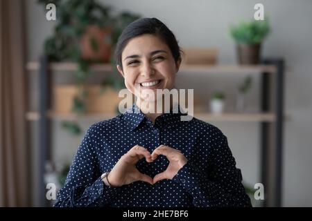 Felice donna indiana millenaria facendo mano dito cuore Foto Stock