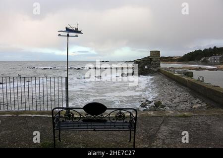 Dunure, South Ayrshire, Scozia , Regno Unito. Le onde del mare si infrangono sulla parete del porto proteggendo l'ingresso. Weathervain barca da pesca Foto Stock