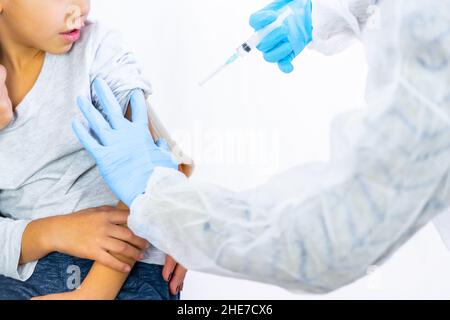 Una dottoressa calma il bambino con la madre prima dell'iniezione del vaccino. Vaccinazione dei bambini. Immunizzazione nel coronavirus pandemico, co Foto Stock