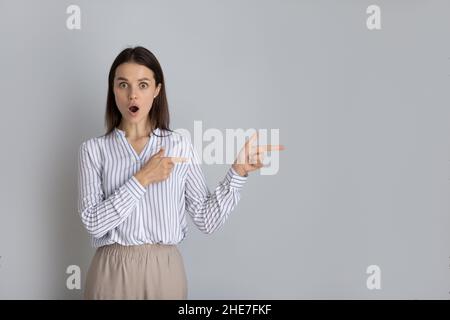Scioccato eccitato sorpresa giovane donna che fa pubblicità alla vendita Foto Stock