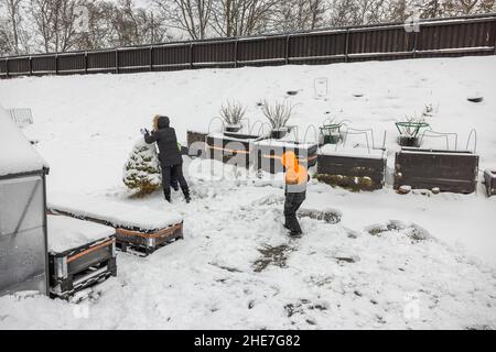 I bambini con la madre giocano in giardino in una gelida giornata invernale. Svezia. Foto Stock