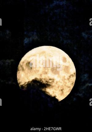 Le nuvole oscurano parzialmente la Luna della raccolta piena che si innalza sulle Montagne Rocciose, Salida, Colorado, USA Foto Stock