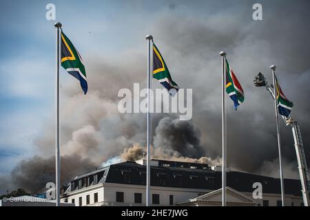 Città del Capo, Sudafrica, 01-03-2022: Il Parlamento del Sudafrica brucia per il secondo giorno. Quattro bandiere nazionali stanno volando davanti al fuoco Foto Stock