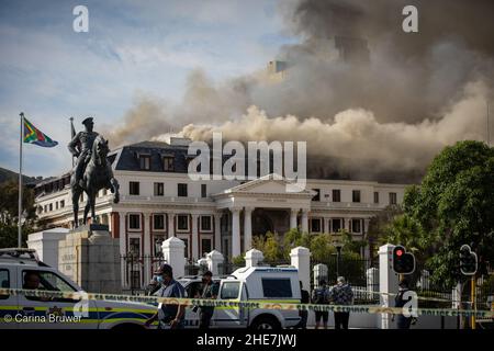 Città del Capo, Sudafrica, 01-03-2022: Il Parlamento del Sudafrica è in fiamme. Una statua di Louis Botha guarda sopra mentre un vigile del fuoco sfugga la bizzarro Foto Stock