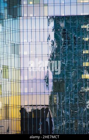 Riflessioni sul vetro delle finestre di un edificio di uffici. Foto Stock