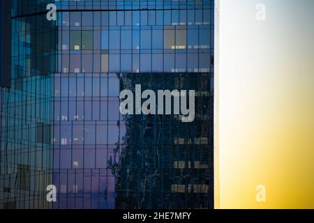 Riflessioni sul vetro delle finestre di un edificio di uffici. Foto Stock