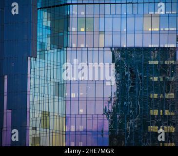 Riflessioni sul vetro delle finestre di un edificio di uffici. Foto Stock
