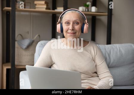 Ritratto di sorridente bella donna di hoary pensionato maturo in cuffie. Foto Stock