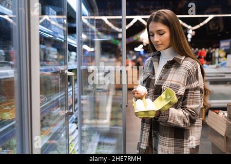 La giovane donna acquista uova di pollo in un supermercato. Ragazza al negozio di alimentari Foto Stock