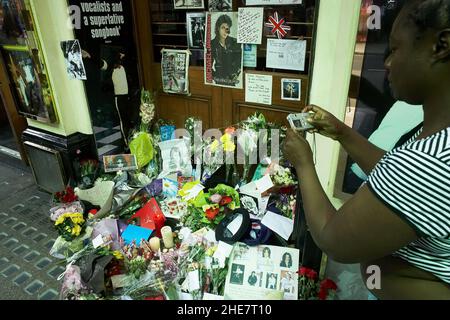 Fan scattare foto di fiori, candele, immagini, giocattoli e lettere di Tribute lasciato in un santuario per Michael Jackson, fuori da un teatro di Londra . Foto Stock