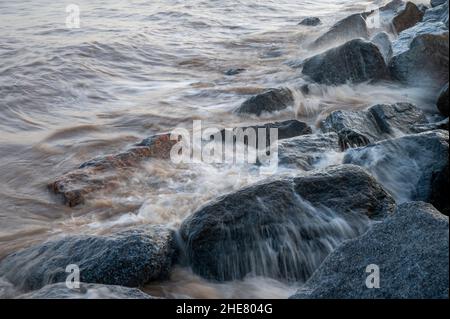 Onde che si infrangono sulle rocce delle difese marine a Skegness, Lincolnshire, Regno Unito Foto Stock